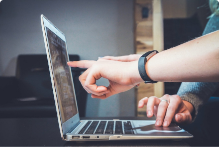 Two hands pointing at a laptop screen